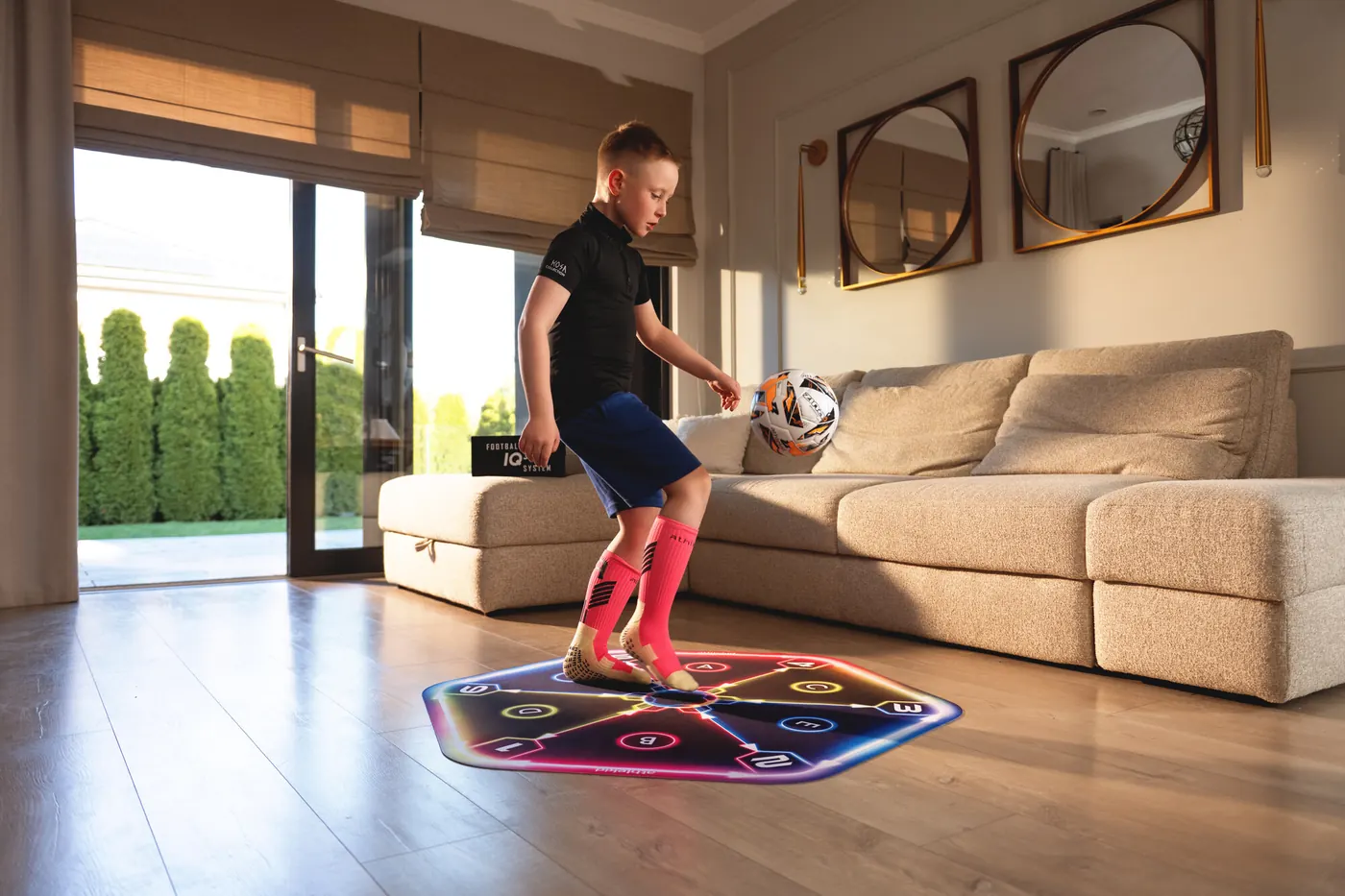 A boy juggling a ball on the Athlekid training mat in a living room